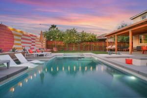 a swimming pool in a yard with chairs and a house at Colorful house with Amazing Backyard in Coachella