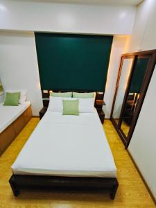 バギオにあるCEDAR PEAK by AWESOME STAY in Baguioの緑の壁のベッドルーム1室(ベッド2台付)