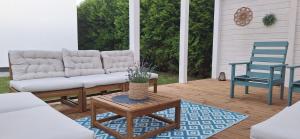 un porche avec un canapé et deux chaises bleues dans l'établissement NA FALI Pokoje i Apartamenty, à Wicie