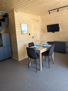 a room with a table with chairs and a television at Domki Słodka Magnolia in Karwia