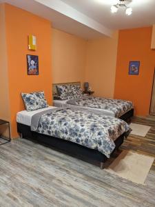 two beds in a room with orange walls at Апартамент Аладин- Център Враца in Vratsa