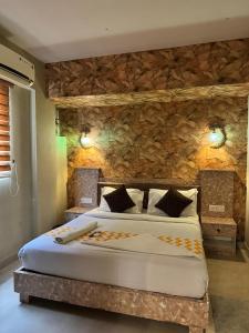 a bedroom with a large bed and a stone wall at KORAMANGALA SUITEs in Bengaluru