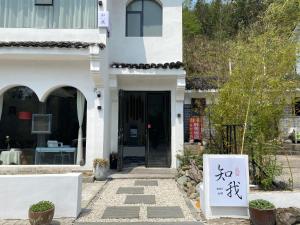 TaipingZhiwo B&B Fanjingshan East Branc的一座白色的房子，前面有一块牌子