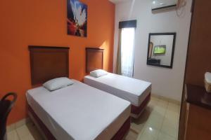 two beds in a room with orange walls at Hotel O Classic Guesthouse in Balikpapan