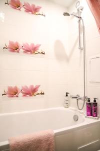 a bathroom with a bath tub with pink flowers on the wall at Magnolija in Liepāja