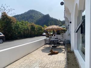 TaipingZhiwo B&B Fanjingshan East Branc的一只狗躺在人行道上，旁边是一张带伞的桌子