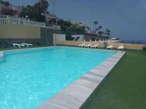 a swimming pool with chairs on the side of a building at Lucas beach in Mogán