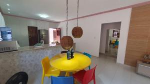 une table jaune dans une cuisine avec des chaises colorées dans l'établissement Casa ROSA in Antunes Maragogi, à Maragogi