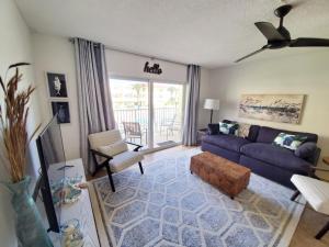 Una sala de estar con un sofá azul y una silla. en Ocean View 2 Bed, 2 bath, Steps to the Beach - Spanish Trace 240, en Coquina Gables