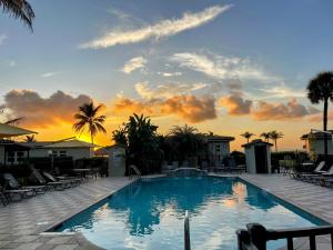 a swimming pool with a sunset in the background at Royal Flamingo Villas in Hillsboro Beach
