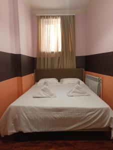 a bedroom with a bed with white sheets and a window at Dreamer's Den Hostel and Tours in Yerevan