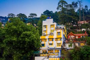 a white and yellow building on a hill at Shalom Backpackers Shimla in Shimla