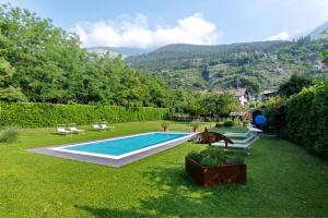 a swimming pool in a yard with lawn chairs at New Residence Schnatzhof Schlanders in Silandro