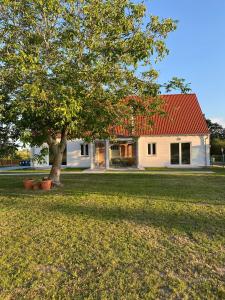 una casa blanca con techo rojo y un árbol en Apartamenty Kukinia33, en Kukinia