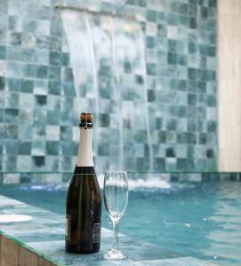 a bottle of wine and a glass next to a swimming pool at Cozy big house in Paracas