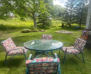 a glass table with four chairs around it at Sawyer Cove Cottage in Jonesport