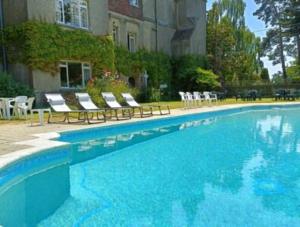a large blue swimming pool with chairs and a building at Arbour View in Polegate