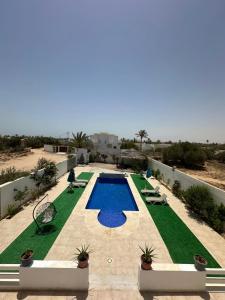 a view of a pool with green grass at Villa Line Midoun sans vis-à-vis in Taguermess