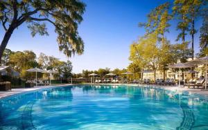 a large blue swimming pool with chairs and umbrellas at 4 Bedroom Wilson Village Home 6 in Bluffton