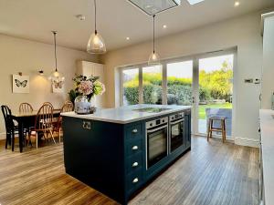 cocina con isla azul y comedor en Springfield, en Milford on Sea