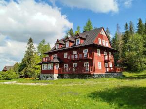 a large red house on a grassy field at Apartament Górska Przystań - Willa Marysin in Bukowina Tatrzańska