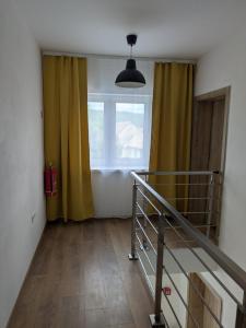 a room with a staircase and a window with yellow curtains at Villa Hrachovo in Hrachovo