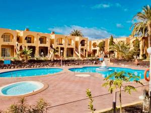un complexe avec piscine et palmiers dans l'établissement Click&Guest - Golden Sands in Maspalomas, à San Fernando