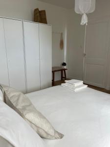 a bedroom with a white bed with white cabinets and books at Le Petit Cottage - Appartement Centre-Ville & Plage in Concarneau