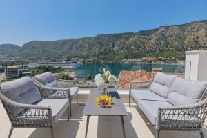 a patio with chairs and a table with a view of the water at Berge Apartments in Kotor