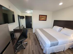 Un dormitorio con una cama, un escritorio y una silla. en The Suite Inn Minot, en Minot