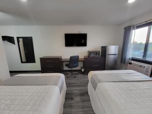 a hotel room with two beds and a desk and a television at The Suite Inn Minot in Minot