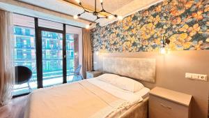 1 dormitorio con 1 cama con pared de flores en Apartments 1 line sea WYN RESIDENS, en Batumi