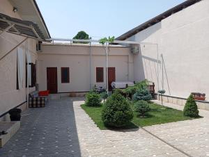 a courtyard of a house with trees and bushes at Navruz Hostel in Samarkand