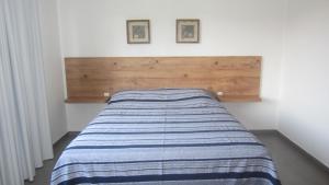 a bed with a blue and white striped blanket on it at Residencial Marbella in Bombinhas