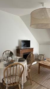 ein Esszimmer mit Tisch und Stühlen und einem Fernseher in der Unterkunft Le Petit Cottage - Appartement Centre-Ville & Plage in Concarneau
