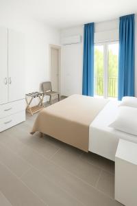 a bedroom with a white bed and blue curtains at La Conchiglia Apartment Villa Margi in Santo Stefano di Camastra