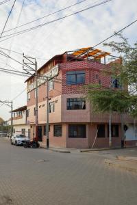 a brick building on a street with cars parked in front at Hospedaje Los Organos in Los Órganos