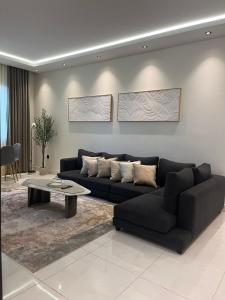 ein Wohnzimmer mit einer schwarzen Couch und einem Tisch in der Unterkunft شقة فاخرة مع إطلالة مركزية بالقرب من الحرم والخدمات in Medina