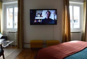 ein Schlafzimmer mit einem an der Wand hängenden TV in der Unterkunft Magnifique studio au centre historique in Mulhouse