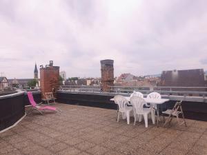 eine Gruppe weißer Stühle und Tische auf einem Dach in der Unterkunft Magnifique studio au centre historique in Mulhouse