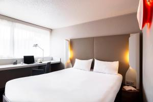 a bedroom with a large white bed and a window at Campanile Montesson - Le Vésinet in Montesson