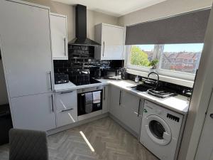 a kitchen with white cabinets and a washer and dryer at 3 bedroom Falkirk flat in Falkirk