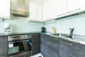 La cuisine est équipée de placards blancs et d'un évier en acier inoxydable. dans l'établissement Spacious Apartment for 8 with Sauna, à Kerava