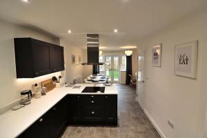 a kitchen with black cabinets and white counter tops at Lower Townhouse, Exeter in Alphington
