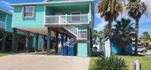 Casa azul con balcón y palmeras en Tipsy Turtle - relax, unwind, you're on turtle time, en Port Aransas