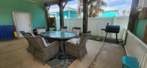 un patio con mesa de cristal, sillas y parrilla en Tipsy Turtle - relax, unwind, you're on turtle time, en Port Aransas