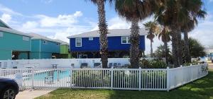Una valla blanca delante de una casa con palmeras. en Tipsy Turtle - relax, unwind, you're on turtle time, en Port Aransas
