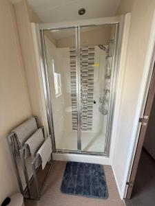 a bathroom with a shower with a blue rug at Luxury 2 bedroom Caravan Pets stay Free in Hunstanton