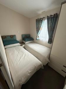 two beds in a small room with a window at Luxury 2 bedroom Caravan Pets stay Free in Hunstanton