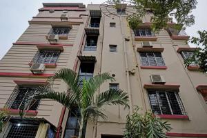 a tall building with windows and a palm tree at Hotel O Sai City inn in Jādabpur